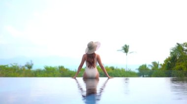 Otelde yüzme havuzunda dinlenen Asyalı güzel bir kadının görüntüsü.