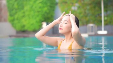 Otelde yüzme havuzunda dinlenen Asyalı güzel bir kadının görüntüsü.