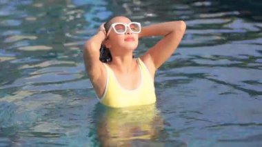 Otelde yüzme havuzunda dinlenen Asyalı güzel bir kadının görüntüsü.