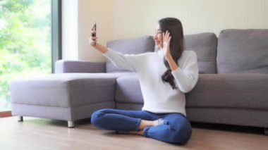 Güzel Asyalı kadının evde akıllı telefon kullandığının görüntüleri.