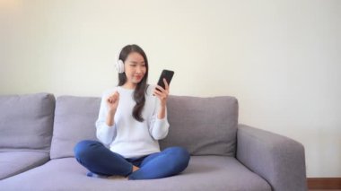Evde kulaklıkla müzik dinleyen Asyalı güzel bir kadının görüntüleri.