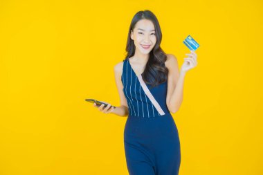 Renkli arka planda akıllı cep telefonuyla güzel Asyalı kadın gülümsemesi