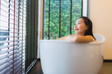Güzel bir Asyalı kadın portresi mutlu bir gülümseme rahatla banyo küvetinde banyo yap.