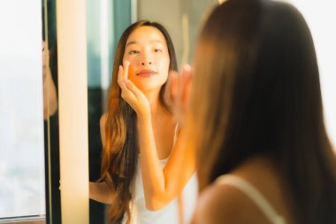 Güzel bir Asyalı kadın portresi. Banyo içinde yüzüne ve yüzüne krem sür.