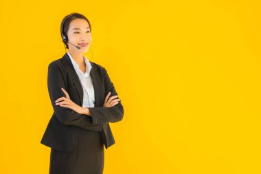 Portre güzel genç Asyalı kadın kulaklık ya da çağrı merkezi için kulaklık ya da tele pazarlama sarı izole arka planda.