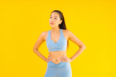 Sarı izole edilmiş arka planda spor giysili güzel Asyalı kadın portresi egzersize hazır.