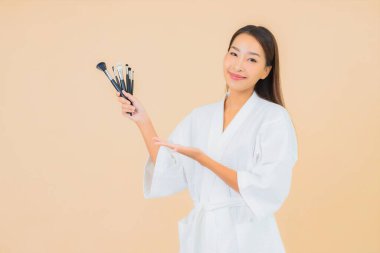 Renkli arka planda makyaj fırçası olan güzel bir Asyalı kadın portresi.