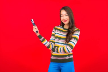 Kırmızı arka planda makyaj fırçası ve makyaj malzemesi olan güzel Asyalı kadın portresi.