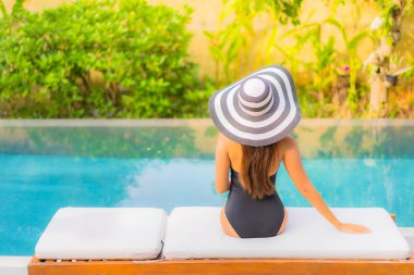 Güzel bir Asyalı kadının portresi tatil için yüzme havuzunda rahatlıyor.