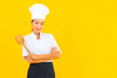 Sarı izole arkaplanda spatulası olan güzel, genç Asyalı şef kadın portresi.
