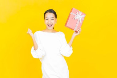 Güzel bir Asyalı kadının portresi. Arka planda kırmızı hediye kutusuyla gülümsüyor.