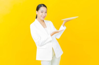 Güzel Asyalı bir kadının portresi. Arka planda boş tabak tabağıyla gülümsüyor.