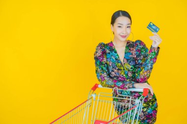Renkli arka planda süpermarketten alınmış market sepetiyle gülümseyen güzel Asyalı kadın portresi.