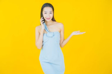 Renkli arka planda akıllı cep telefonuyla güzel Asyalı kadın gülümsemesi