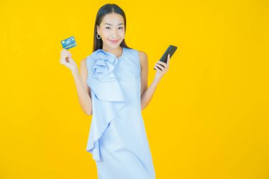 Renkli arka planda akıllı cep telefonuyla güzel Asyalı kadın gülümsemesi