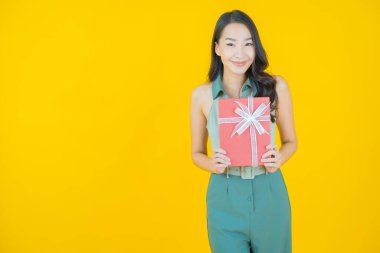 Güzel bir Asyalı kadının portresi. Arka planda kırmızı hediye kutusuyla gülümsüyor.