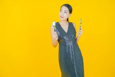 Güzel Asyalı bir kadının portresi kaşıkla ve çatalla gülümsüyor.