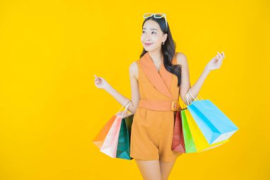 Portre güzel Asyalı kadın tebessümü ile renk arka planında alışveriş torbası