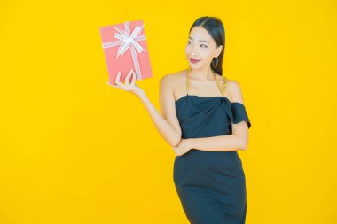 Güzel bir Asyalı kadının portresi. Arka planda kırmızı hediye kutusuyla gülümsüyor.