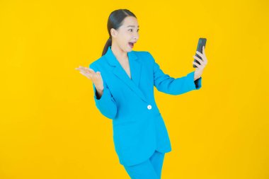 Renkli arka planda akıllı cep telefonuyla güzel Asyalı kadın gülümsemesi