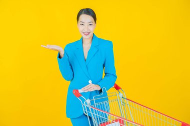 Renkli arka planda süpermarketten alınmış market sepetiyle gülümseyen güzel Asyalı kadın portresi.