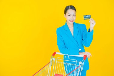 Renkli arka planda süpermarketten alınmış market sepetiyle gülümseyen güzel Asyalı kadın portresi.