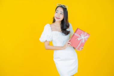 Güzel bir Asyalı kadının portresi. Arka planda kırmızı hediye kutusuyla gülümsüyor.