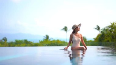 Otelde yüzme havuzunda dinlenen Asyalı güzel bir kadının görüntüsü.