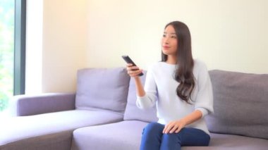 Güzel Asyalı bir kadının uzaktan kumandalı televizyon izlediği görüntüler.