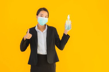 Güzel bir iş kadını portresi. Maske takıyor. Korunmak için alkol jeli kullanıyor.