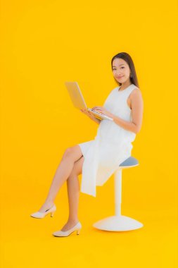 Sarı izole edilmiş arka planda bilgisayarlı güzel Asyalı kadın portresi.