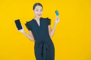 Güzel bir Asyalı kadının portresi. Renkli kredi kartıyla gülüyor.