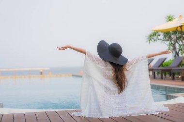 Asyalı genç bir kadının portresi mutlu bir gülümseme otel tatil beldesinde yüzme havuzunda rahatlamak