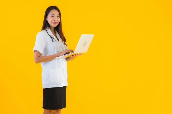 形象漂亮的年轻亚洲医生女人在黄色孤立的背景下使用笔记本电脑或笔记本电脑 — 图库照片