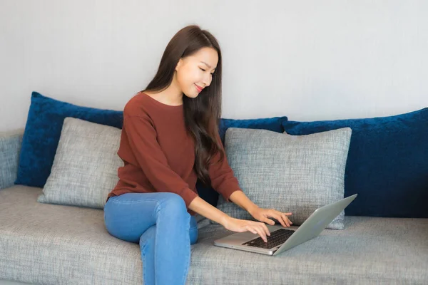 漂亮的年轻亚洲女人在客厅的沙发上使用电脑笔记本电脑 — 图库照片