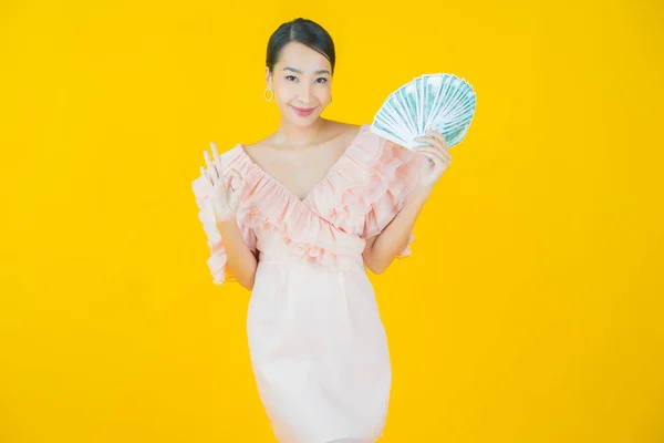 亚洲年轻貌美的女人面带微笑 带着大量的现金和金钱的色彩背景 — 图库照片