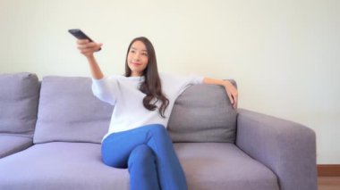 Güzel Asyalı bir kadının uzaktan kumandalı televizyon izlediği görüntüler.