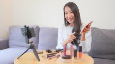 Güzel Asyalı makyaj blogcusunun kanepede video çekerken ki görüntüleri.