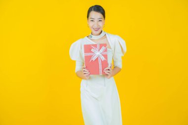 Güzel bir Asyalı kadının portresi. Arka planda kırmızı hediye kutusuyla gülümsüyor.