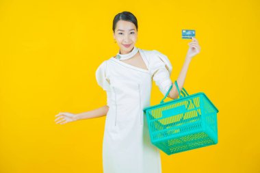 Renkli arka planda süpermarketten alınmış market sepetiyle gülümseyen güzel Asyalı kadın portresi.