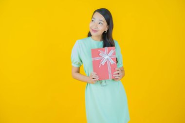 Güzel bir Asyalı kadının portresi. Arka planda kırmızı hediye kutusuyla gülümsüyor.