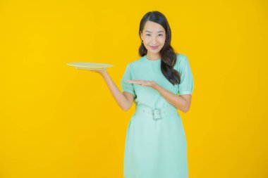 Güzel Asyalı bir kadının portresi. Arka planda boş tabak tabağıyla gülümsüyor.