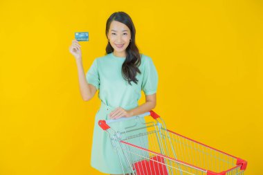 Renkli arka planda süpermarketten alınmış market sepetiyle gülümseyen güzel Asyalı kadın portresi.