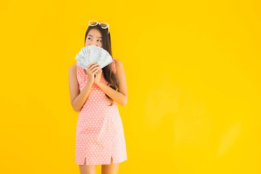 Sarı izole edilmiş arka planda bir sürü parası ve parası olan güzel Asyalı kadın portresi.