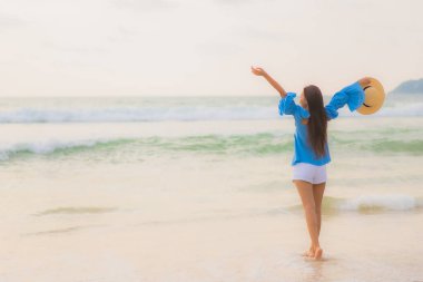Güzel bir Asyalı kadın portresi. Gün batımında deniz kıyısında rahatça gülümse.