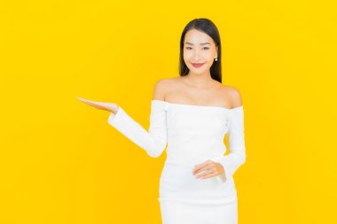 Portre güzel genç iş kadını gülümseyen ve eylem sarı arka planlı Asyalı kadın