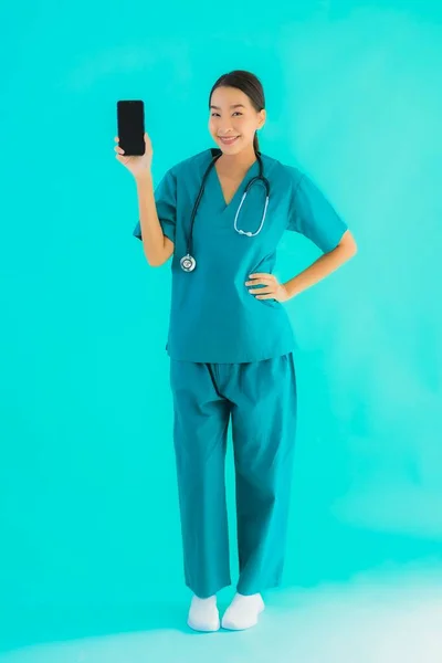 肖像画美しい若いアジアの医師の女性ショースマートフォン上の青隔離された背景 — ストック写真