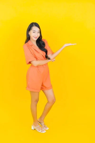 亚洲年轻貌美的女子面带微笑 黄褐色背景的动作 — 图库照片