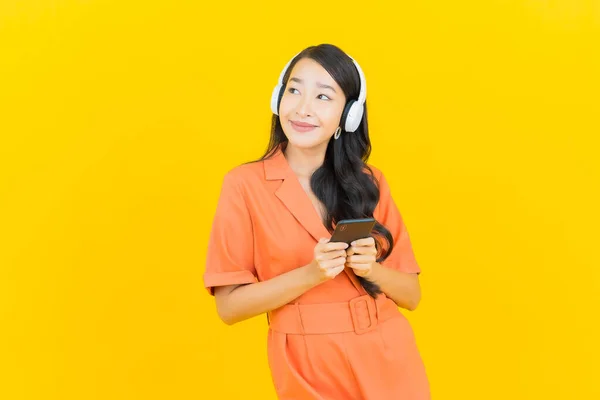 Kulaklık Akıllı Cep Telefonlu Güzel Asyalı Kadın Portresi Sarı Arka — Stok fotoğraf