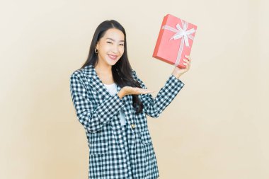 Güzel bir Asyalı kadının portresi. Arka planda kırmızı hediye kutusuyla gülümsüyor.